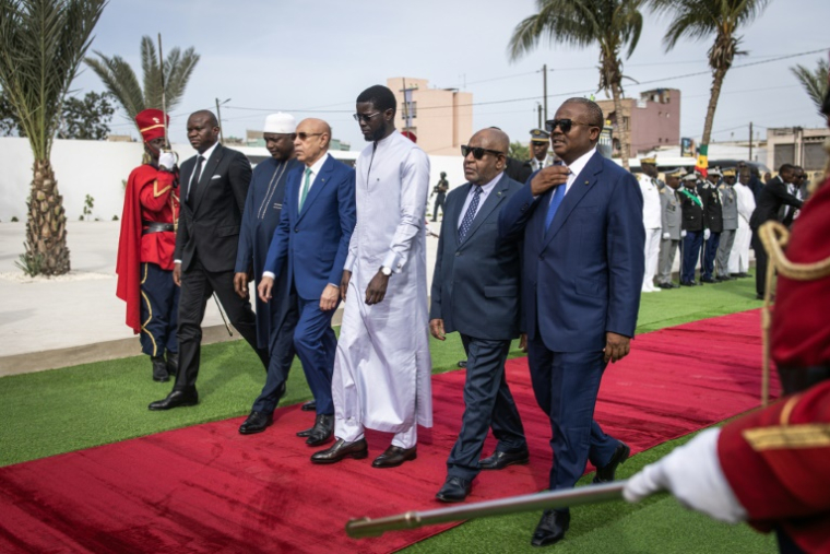 Le président sénégalais, Bassirou Diomaye Faye, en blanc, au centre, entouré de gauche à droite par le président du Gabon Brice Oligui Nguem, le président de la Gambie Adama Barrow, le président mauritanien Mohamed Ould Ghazouani, le président de la Guinée-Bissau Umaro Sissoco Embaló et le président de l'Union des Comores Azali Assoumani au cimetière de Thiaroye le 1er décembre 2024  ( AFP / JOHN WESSELS )