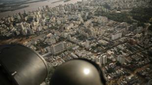 Un militaire observe depuis un hélicoptère la ville inondée dde Porto Alegre, dans l'État du Rio Grande do Sul, au Brésil, le 8 mai 2024 ( AFP / Carlos FABAL )