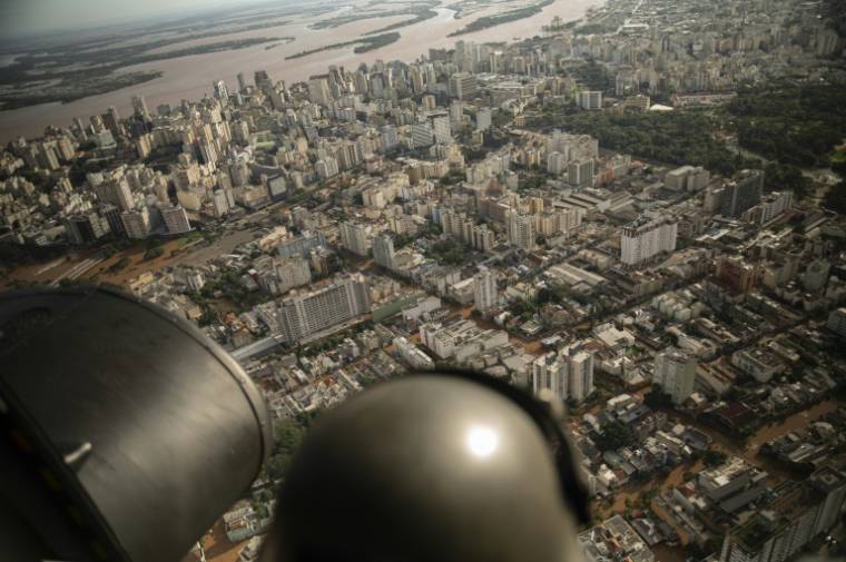 Un militaire observe depuis un hélicoptère la ville inondée de Porto Alegre, dans l'État du Rio Grande do Sul, au Brésil, le 8 mai 2024 ( AFP / Carlos FABAL )