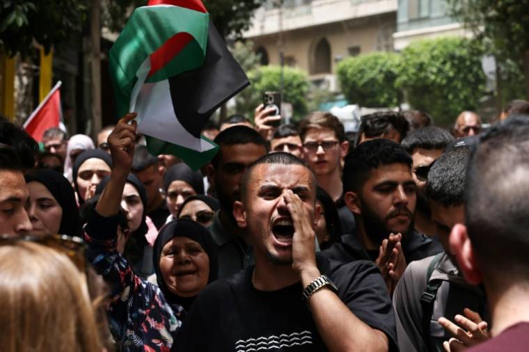 Des personnes scandent des slogans lors d'un rassemblement à Ramallah, en Cisjordanie occupée, le 27 mai 2024, après une frappe nocturne ayant mis le feu à des tentes occupées par des Palestiniens déplacés dans un camp à Rafah, dans la bande de Gaza ( AFP / Zain JAAFAR )