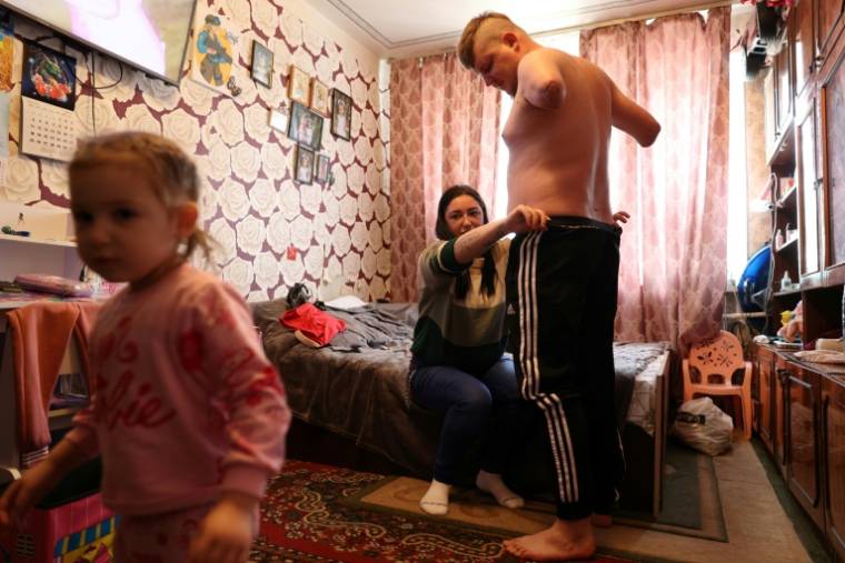 Veronika Koutcherenko aide son mari Valeriï, amputé des deux avant-bras après une blessure au combat, à s'habiller, dans leur appartement de Bila Tserkva, au sud de Kiev, le 4 avril 2024 ( AFP / Anatolii STEPANOV )