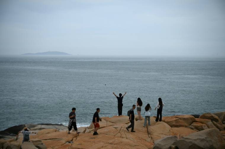 Des personnes regardent le détroit de Taïwan sur un site touristique appelé "68 milles marins" situé sur l'île de Pingtan, dans la province chinoise du Fujian, dans le sud-est du pays, à l'endroit de Chine continentale le plus proche de l'île principale de Taïwan, le 24 mai 2024. ( AFP / Greg Baker )