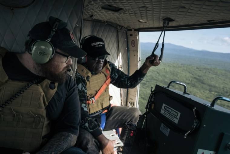 L'Américain Caleb Weiss (g), employé de la fondation américaine Bridgeway, et le colonel Udju des FARDC, survolent à bord d'un hélicoptère les bastions des ADF, le 8 mai 2024 au-dessus du territoire de Beni, dans la province du Nord-Kivu, dans l'est de la RDC ( AFP / ALEXIS HUGUET )