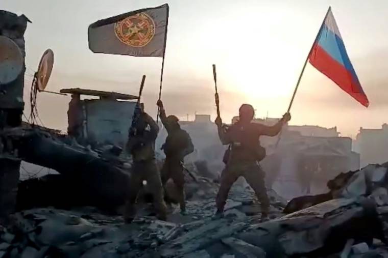 Image tirée d'une vidéo postée sur le compte Telegram de la société Concord, liée à Evguéni Prigojine, montrant des mercenaires du groupe paramilitaire russe Wagner tenant un drapeau russe à Bakhmout, le 20 mai 2023, en Ukraine ( Telegram @concordgroup_official / Handout )