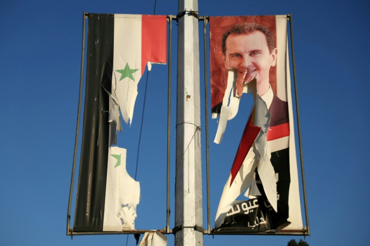 Un drapeau national syrien et un portrait du président syrien Bachar al-Assad dséchirés par des combattants antigouvernementaux dans la ville d'Alep, dans le nord de la Syrie, le 30 novembre 2024 ( AFP / Omar HAJ KADOUR )