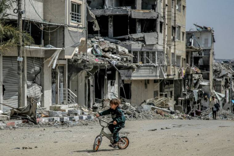 Un garçon sur une bicyclette au milieu des destructions dans une rue de la ville de Gaza, le 27 mars 2024 ( AFP / - )