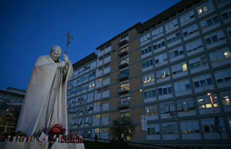 Des bougies sont posées au pied de la statue de Jean Paul II devant l'hôpital Gemelli où se trouve le pape François, à Rome, le 22 février 2025 ( AFP / Alberto PIZZOLI )