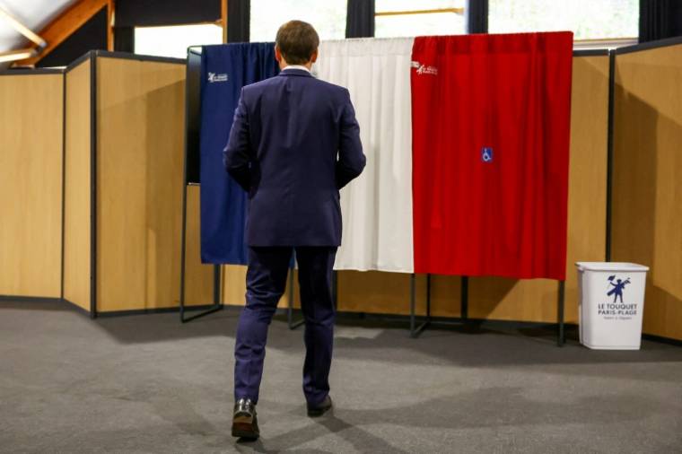 Le président français Emmanuel Macron rentre dans l'isoloir pour voter aux élections européennes, le 9 juin 2024 au Touquet, dans le Pas-de-Calais  ( POOL / Hannah McKay )