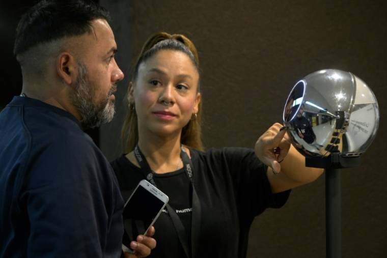 Une employée aide un homme à se faire scanner l'iris avec un dispositif de numérisation de données biométriques en échange de cryptomonnaie, le 22 mars 2024 à Buenos Aires, en Argentine ( AFP / Juan Mabromata )