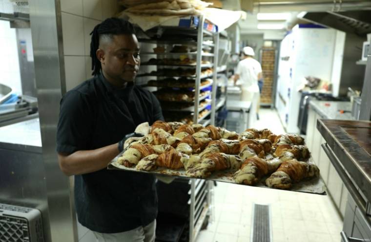Un employé sort du four des crookies, un croissant français traditionnel mélangé à de la pâte à cookies, dans la pâtisserie de Stéphane Louvard, le 2 avril 2024 à Paris ( AFP / Thomas SAMSON )