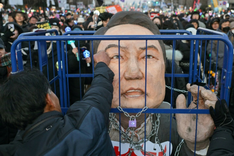 Un manifestant appelant au limogeage du président Yoon Suk Yeol frappe une effigie du chef de l'Etat, le 14 décembre 2024 à Séoul ( AFP / ANTHONY WALLACE )