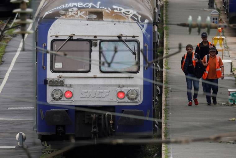 Photo d'archives: Des ouvriers passent devant des trains régionaux TER au dépôt SNCF d'Hellemmes-Lille