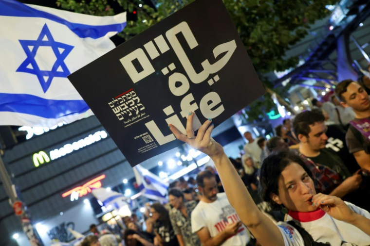 Une manifestante brandit une pancarte lors d'un rassemblement antigouvernemental appelant à agir pour obtenir la libération des otages israéliens retenus à Gaza, devant le ministère de la Défense à Tel-Aviv le 26 octobre 2024 ( AFP / Jack GUEZ )