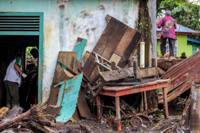Des personnes nettoient une maison endommagée par la boue et les troncs d'arbres emportés par des crues soudaines dans le village de Rambatan, en Indonésie, le 14 mai 2024 ( AFP / ADE YUANDHA )