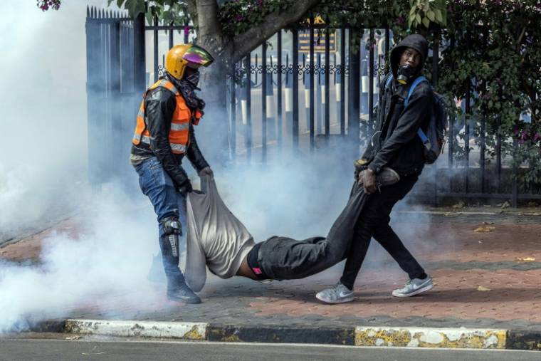 Des manifestants portent un homme blessé près du Parlement à Nairobi, le 25 juin 2024 au Kenya ( AFP / LUIS TATO )