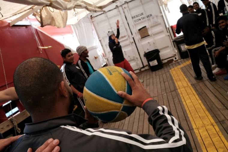 Des migrants originaires du Bangladesh jouent au basket-ball à bord du navire-ambulance Ocean Viking affrété par l'ONG SOS Méditerranée, le 22 mai 2024. ( AFP / Clément MELKI )
