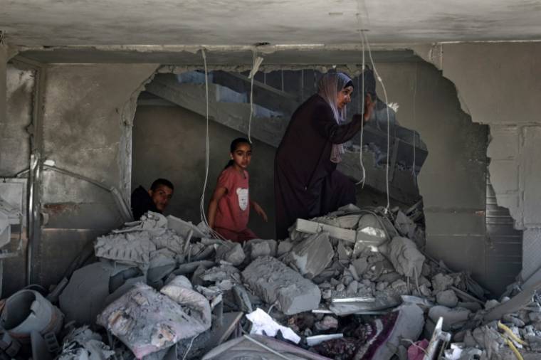 Une Palestinienne et des enfants dans les décombres d'une maison touchée par des bombardements israéliens nocturnes à Rafah, dans le sud de la bande de Gaza, le 20 avril 2024 ( AFP / - )