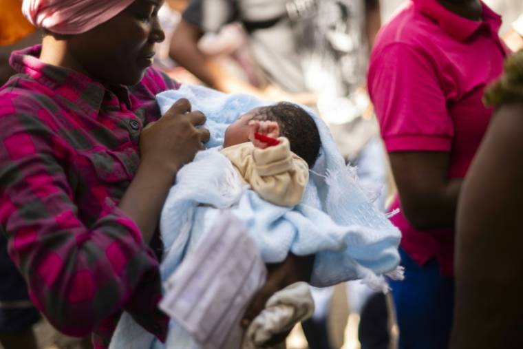 Nehemie Laguerre, son bébé dans les bras, attend une consultation à une clinique mobile de l'Alima, dans une église transformée en camp pour déplacés internes du quartier de Delmas, à Port-Au-Prince, le 11 juin 2024 en Haïti ( AFP / ROBERTO SCHMIDT )