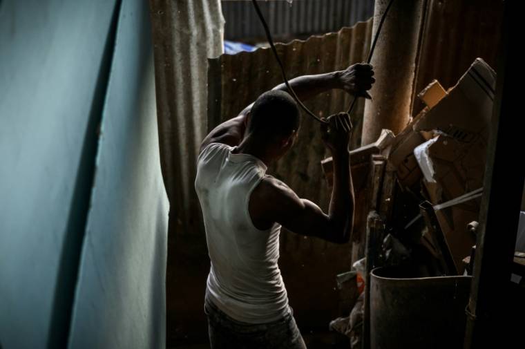 Un homme récupère des matériaux dans le bidonville "Talus 2", dans le nord de Mayotte, promis à une démolition imminente, le 21 mai 2023 ( AFP / Philippe LOPEZ )