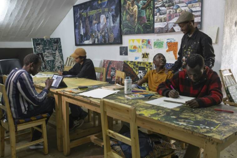 Des membres du collectif "Art for memories" travaillent sur des portraits de victimes du génocide rwandais, le 2 avril 2024 à Kigali ( AFP / Guillem Sartorio )