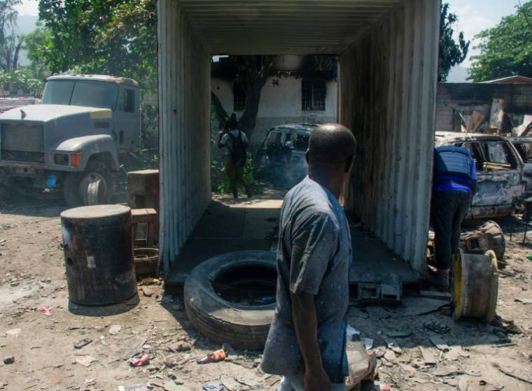 Un homme près de véhicules brûlés près de son garage à Port-au-Prince le 25 mars 2024 ( AFP / Clarens SIFFROY )