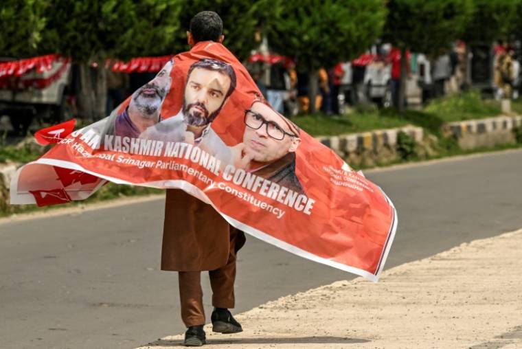 Un partisan de la Conférence Nationale porte une bannière avec des photos de dirigeants du parti lors d'un meeting de campagne électorale à Srinagar, la principale ville du Cachemire administrée par l'Inde, le 11 mai 2024 ( AFP / TAUSEEF MUSTAFA )