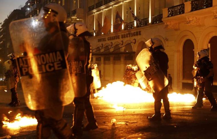 Riot police stand amongst flames from petrol bombs thrown by a small group of anti-austerity demonstrators in Athen