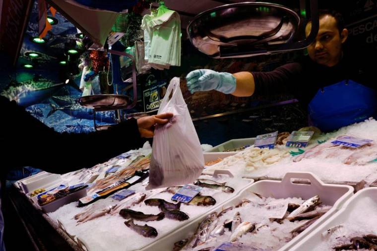 Un poissonnier tend un sac de poisson à un client dans un supermarché alors que le gouvernement espagnol annonce des mesures pour lutter contre l'inflation, à Madrid.