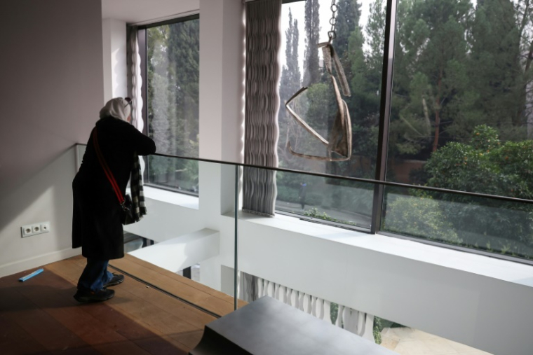 Une femme regarde par la fenêtre d'une des pièces de la résidence du président syrien déchu Bachar al-Assad, dans le quartier Malki à Damas, le 8 décembre 2024 ( AFP / OMAR HAJ KADOUR )