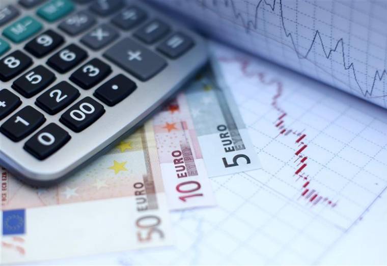 Euro banknotes coins and a calculator are placed on a currency graph and ticker in picture illustration taken in Zenica