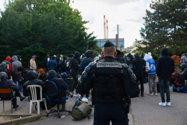 Les personnes évacuées font la queue devant des tables, où les personnels de la préfecture et des services de l'immigration les réorientent  ( AFP / Emmanuel Dunand )