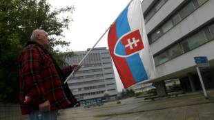 Un partisan du gouvernement avec un drapeau slovaque, le 17 mai 2024, devant l'hôpital où est soigné le Premier ministre Robert Fico, en état grave après une tentative de meurtre quatre jours plus tôt ( AFP / Ferenc ISZA )