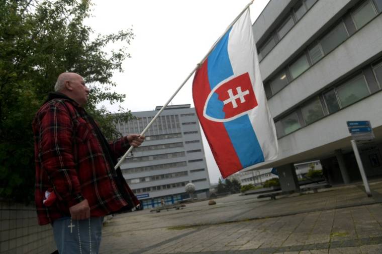 Un partisan du gouvernement avec un drapeau slovaque, le 17 mai 2024, devant l'hôpital où est soigné le Premier ministre Robert Fico, en état grave après une tentative de meurtre quatre jours plus tôt ( AFP / Ferenc ISZA )