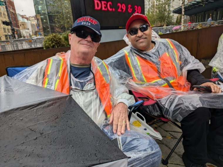 Jeff Dickerson (g) et Nigel Mahabir font la queue avant de pouvoir entrer dans la salle où se tient le dernier meeting de campagne de Donald Trump, le 4 novembre 2024 à Grand Rapids, dans le Michigan ( AFP / Issam AHMED )