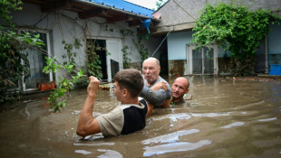 Des habitants portent secours à un vieil homme dans la localité de Slobozia Conachi, victime de crues, le 14 septembre 2024, en Roumanie ( AFP / Daniel MIHAILESCU )