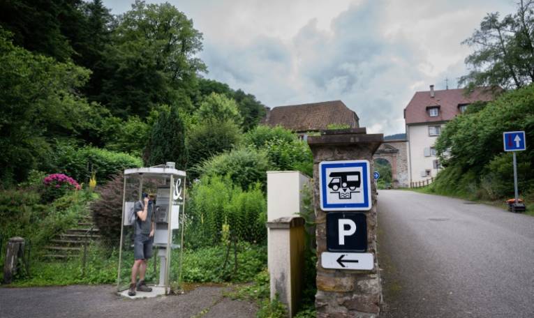 Un homme parle au téléphone dans la dernière cabine téléphonique publique française, à Murbach (Haut-Rhin), le 12 juillet 2024 ( AFP / SEBASTIEN BOZON )