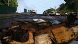 Des véhicules incendiés gisent sur une route menant à Nouméa, dans le territoire français de Nouvelle-Calédonie, le 20 mai 2024 ( AFP / Theo Rouby )