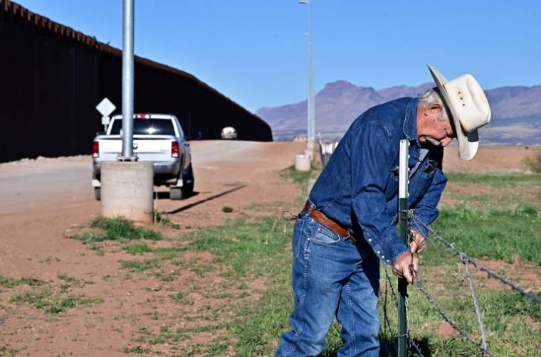 L'éleveur John Ladd ajuste la clôture endommagée délimitant ses terres, le long du mur à la frontière entre les Etats-Unis et le Mexique, le 17 avril 2024 près de Palominas, en Arizona ( AFP / Frederic J. BROWN )