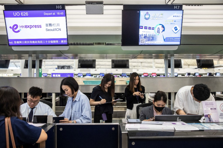 A l'aéroport international de Hong Kong, personnel de l'aéroport enregistre manuellement les passagers en raison d'une panne mondiale de Microsoft. Le 19 juillet 2024. ( AFP / ISAAC LAWRENCE )