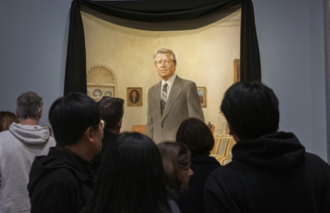 Les visiteurs du musée Smithsonian National Portrait Gallery contemplent un portrait de Norman Rockwell de l'ancien président américain Jimmy Carter dans le bureau ovale de la Maison Blanche, drapé d'un drap de deuil noir, à Washington, aux Etats-Unis, le 30 décembre 2024 ( AFP / ROBERTO SCHMIDT )