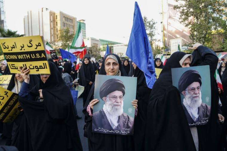 Des Iraniens portant le portrait du guide suprême Ali Khamenei célèbrent l'attaque contre Israël, le 15 avril 2024 à Téhéran ( AFP / ATTA KENARE )