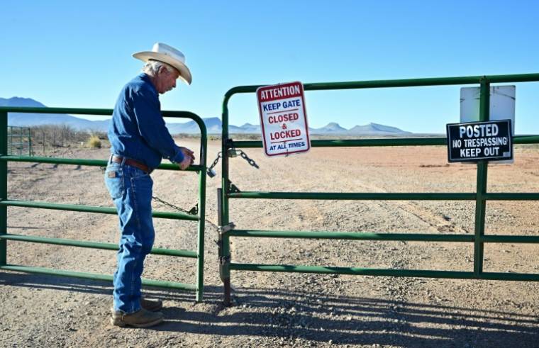 L'éleveur John Ladd ouvre une barrière pour entrer sur les terres de son ranch, proche de la frontière entre les Etats-Unis et le Mexique, le 17 avril 2024 près de Palominas, en Arizona ( AFP / Frederic J. BROWN )