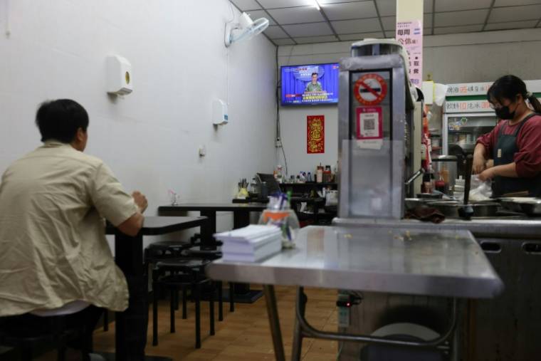 Les clients d'un restaurant de Lieyu, sur l'île de Kinmen,  regardent les informations diffusant une carte délimitant l'encerclement de Taïwan par l'armée chinoise, le 23 mai 2024 ( AFP / I-Hwa CHENG )