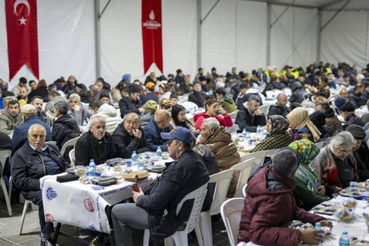 Des fidèles, intallés sous une tente, partagent un repas pour l'iftar offert par la municipalité d'Istanbul, pendant le mois du ramadan, le 15 mars 2024 en Turquie ( AFP / Yasin AKGUL )