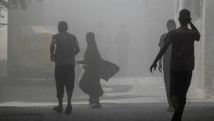 Des Palestiniens marchent dans la fumée et la poussière au camp de Nousseirat, dans le centre de la bande de Gaza, le 8 juin 2024 ( AFP / Bashar TALEB )