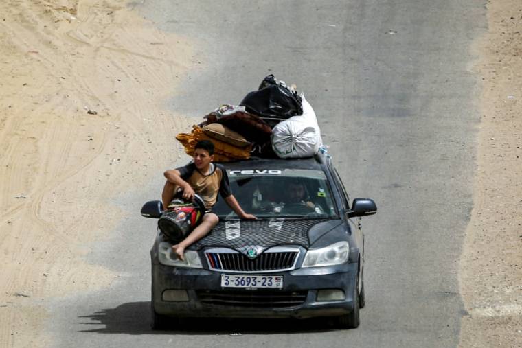 Un garçon est assis sur le capot d'un véhicule chargé d'affaires et à bord duequel une famille palestinienne fuit Rafah vers Khan Younès, dans le sud de la bande de Gaza, le 11 mai 2024 ( AFP / - )
