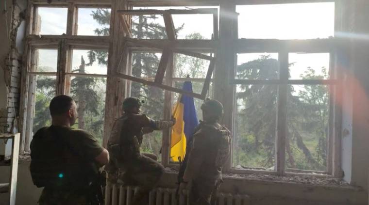 Photo des soldats ukrainiens qui placent un drapeau ukrainien sur un bâtiment, lors d'une opération qui prétend libérer le premier village au milieu d'une contre-offensive à l'est de l'Ukraine