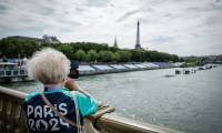 Une bénévole des JO-2024 prend une photo sur le pont des Invalides à côté des tribunes installées sur la Seine à la veille de la cérémonie d'ouverture des Jeux Olympiques 2024, à Paris, le 25 juillet 2024 ( AFP / STEPHANE DE SAKUTIN )