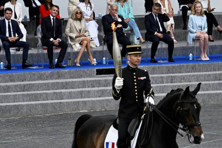 Le cavalier Thibaut Vallette (c), chef des écuyers du Cadre noir de Saumur et médaillé d'or aux JO de Rio en 2016, porte la flamme olympique lors du défilé militaire avenue Foch, le 14 juillet 2024 à Paris ( AFP / JULIEN DE ROSA )