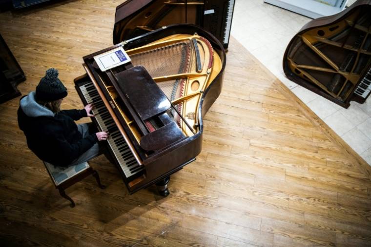Un bénévole essaie un piano dans l'atelier "Pianodrome", le 9 février 2023 à Edimbourg, en Ecosse ( AFP / Andy Buchanan )